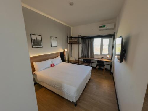 a bedroom with a white bed and a desk and a window at Ibis Puerto General San Martin in Aldao