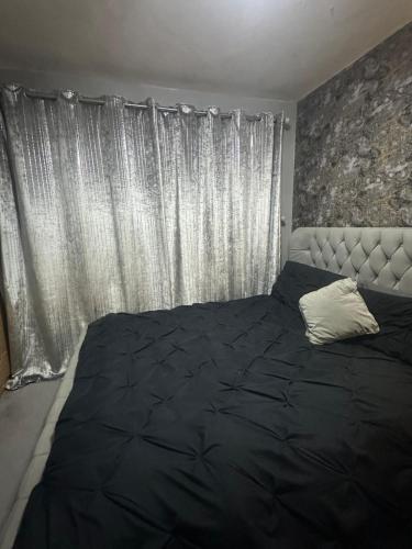 a bedroom with a black bed and a window at Manchester Guesthouse in Manchester