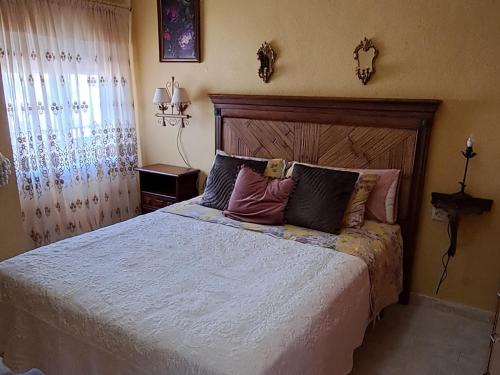 a bedroom with a large bed with a wooden headboard at Old wall House in Olula del Río