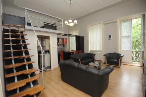 a living room with a black couch and a staircase at Siesta in Kikinda