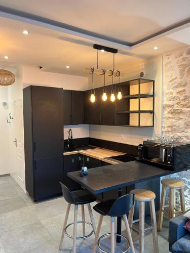 Una cocina con una encimera negra y algunos taburetes de bar. en Moutarde & Elégance de Dijon, en Dijon