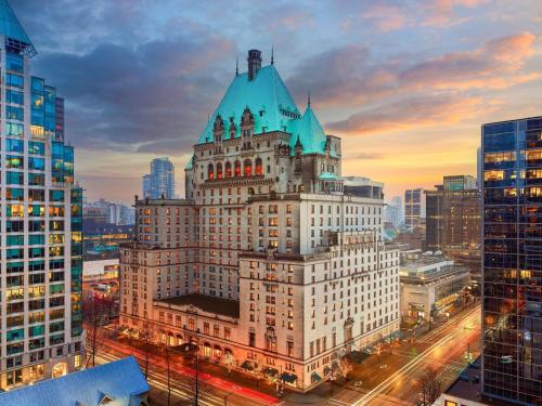 a tall white building with a blue roof in a city at Fairmont Hotel Vancouver in Vancouver