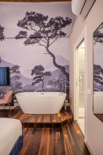 a bathroom with a bath tub and a tree mural at La Maison de Ville & Suite in Piacenza