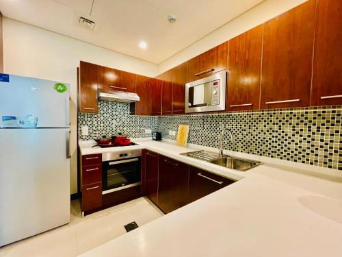 a kitchen with wooden cabinets and a white refrigerator at Modern comfort in a compact spacious studio one or two bedroom retreats in Manama