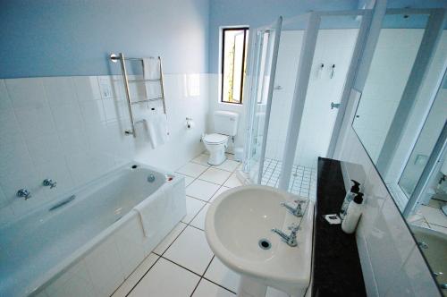 a bathroom with a tub and a toilet and a sink at Fourteenth Green Guest Lodge in East London