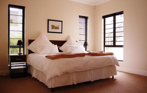 Un dormitorio con una cama con sábanas y almohadas blancas. en Fourteenth Green Guest Lodge, en East London