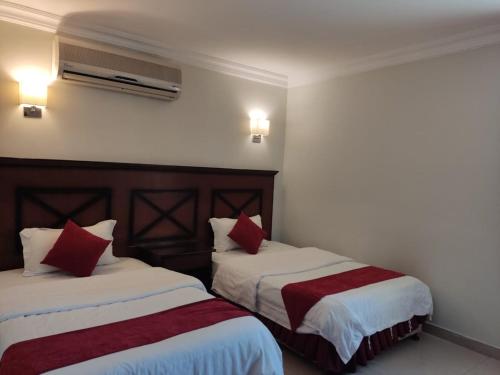 two beds in a hotel room with red pillows at 2 Bed Room near GULF DELMON in Al Mubārakīyah