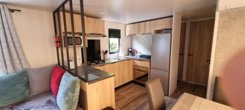 a small kitchen with a refrigerator and a counter at Mobil Home 45 m2 très luxueux 3 ch et 2 sdb - Camping 4 étoiles Les Charmettes 499 PROCHE FUN ZONE- Les Mathes in Les Mathes