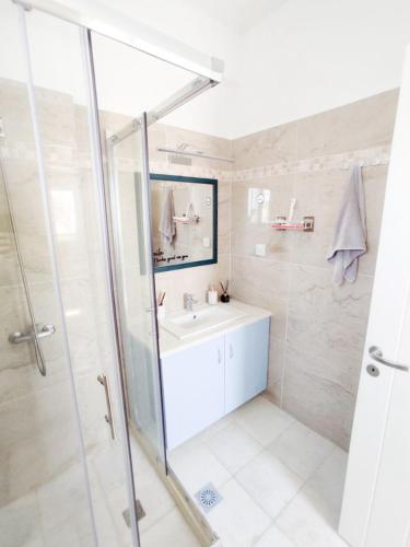 a white bathroom with a sink and a shower at Nympes Melody - Golden Harmony Stay in Parasporos