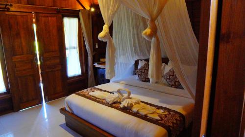 a bedroom with a canopy bed with animals on it at Villa Lumbung Sidemen in Sidemen