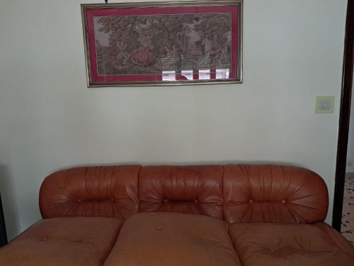 a brown leather couch against a white wall with a picture at appartamento con balcone in Carpineto Romano