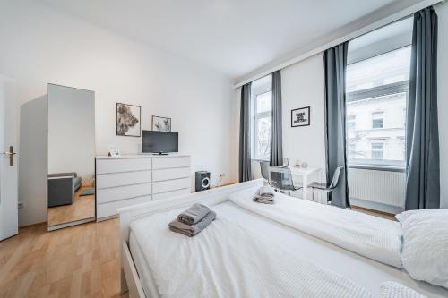 a white bedroom with a bed and a large window at Central Cosy Stylish Apartment in Vienna