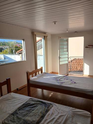 a bedroom with two beds and a window with a balcony at Sobrado Mãezinha Aparecida in Aparecida