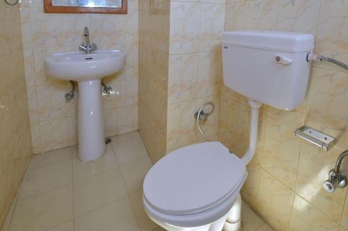 a bathroom with a white toilet and a sink at Sarthak Home Stay, Beautiful Valley view of Mountain in Jagatsukh