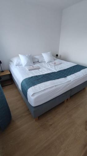a large bed with white sheets and a blue blanket at Apartament I Na Słonku in Dzierzgoń
