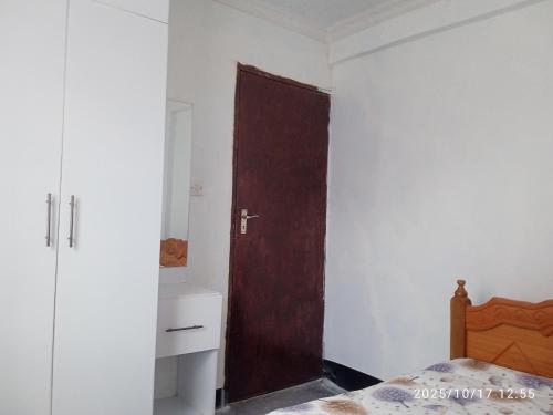 a bedroom with a wooden door and a bed at Polycap Cottage Home in Murangʼa
