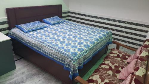 a bed with two blue pillows on top of it at Radha Ras Homestay in Barsāna