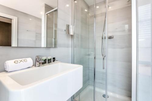 a white bathroom with a sink and a shower at Exe Ramblas Boquería in Barcelona