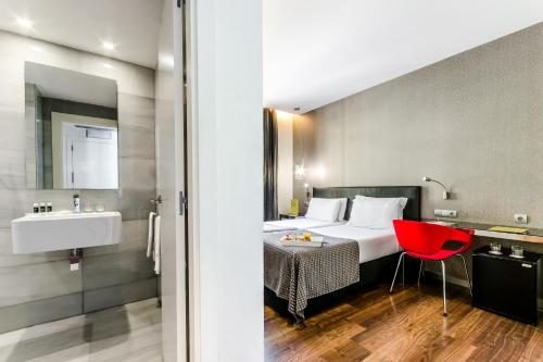 Habitación de hotel con cama y silla roja en Exe Ramblas Boquería, en Barcelona