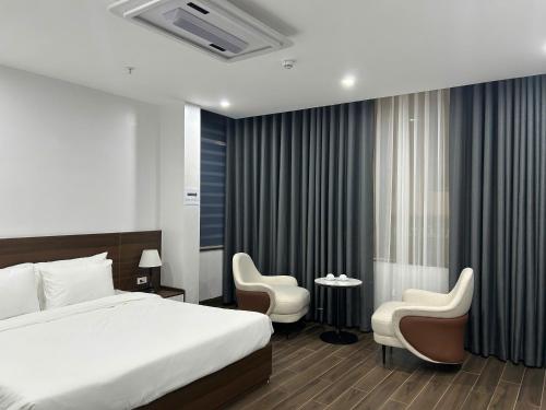 a hotel room with a bed and two chairs at Elegant Hotel in Hanoi