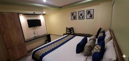 a bedroom with a bed with blue pillows and a television at Hotel SVA in Sitam Petta