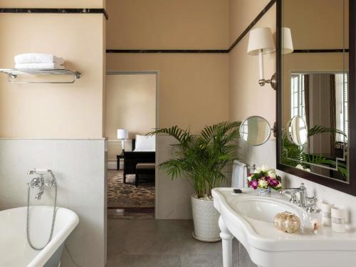 Un baño con bañera, lavabo y espejo. en Raffles Hotel Le Royal, en Phnom Penh
