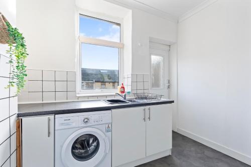 a white kitchen with a washing machine and a window at Haven on the Hill - FREE Parking & Great for Groups in Abertillery