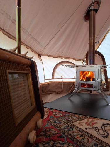 a stove in a tent with a fire in it at Tente glamping "Explorateurs" à la Ferme de la Chevêche in Fosses-La-Ville