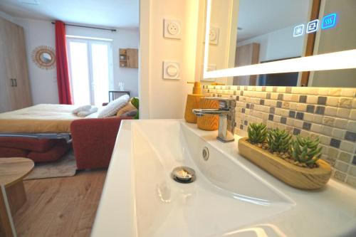 Un baño con lavabo y un dormitorio con cama. en Studio neuf parking gratuit 15 minutes de Lyon, en Francheville