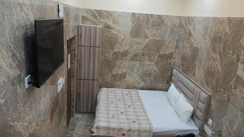 a small bed in a room with a stone wall at Marquis Luxe Guest House in Kolkata