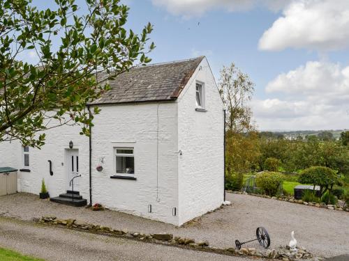 a white house with a window and a yard at Airdside Cottage in Crossmichael