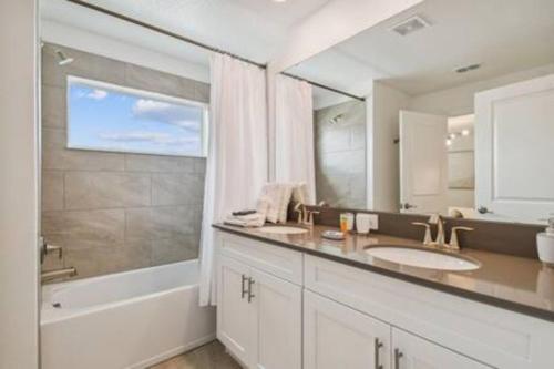 a bathroom with a sink and a tub and a mirror at Storey Lake 4BR/3BA Private Pool in Kissimmee