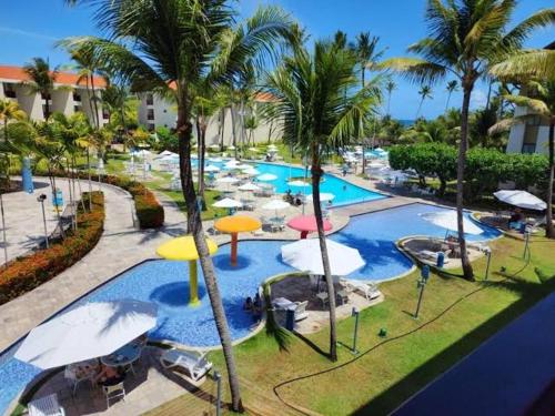 a large swimming pool with umbrellas in a resort at Flat Marulhos Resort - Porto de Galinhas in Ipojuca