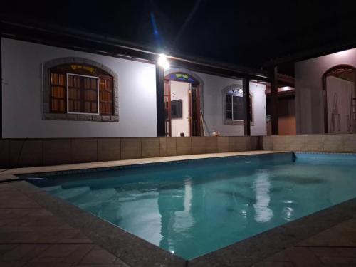 une piscine la nuit dans une maison dans l'établissement Casa com Piscina no Centro de Unamar em Cabo Frio, à Cabo Frio