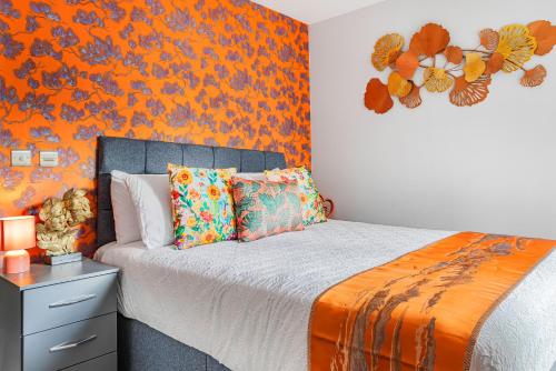 a bedroom with a bed with an orange wall at Luxurious Flat at Leicester Town in Leicester