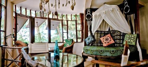a room with a bed and a table and windows at Utupoa in Matemwe