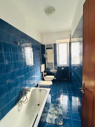 a blue tiled bathroom with two toilets and a tub at sole in Novara