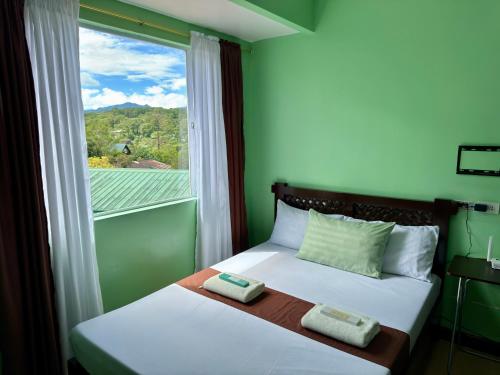 a bedroom with two beds and a window with a view at Albergo Hotel - Studio Condo Unit - Baguio Transient in Baguio