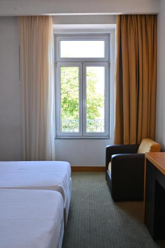 a hotel room with a bed and a window at Hotel Bagoeira in Barcelos