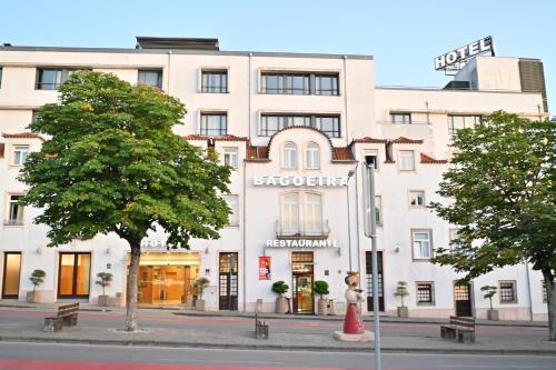 a large white building on a city street with trees at Hotel Bagoeira in Barcelos