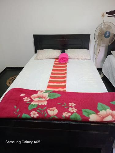 a bed with a red and white blanket on it at Ella Cool Air Cabana in Ella