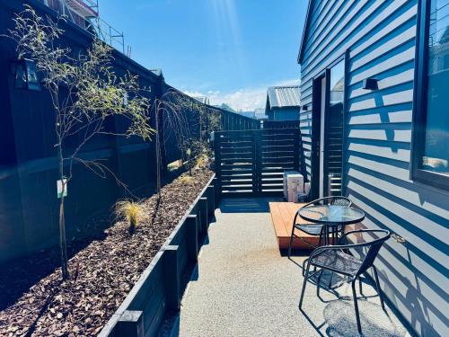 a patio with two chairs and a table next to a building at Hiking Golf Skiing Lake Remarkables 7 Min Airport in Queenstown