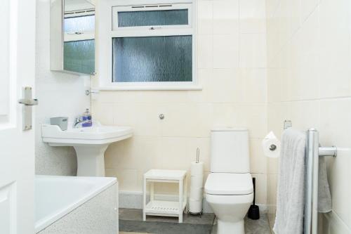 a white bathroom with a toilet and a sink at Airport Home, Free Parking, Sleeps 6, Near City in EDI