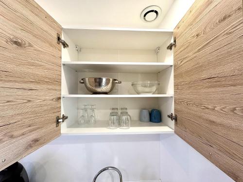 a kitchen cabinet with wooden doors and glassware at Charmant Studio - Centre Douai - Netflix - 2 pers in Douai