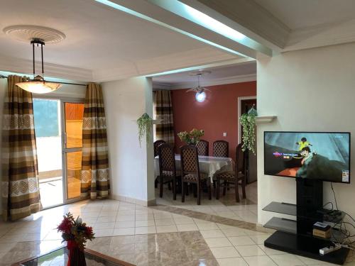 a living room with a tv and a dining table at Appartement haut standing Mimboman in Yaoundé