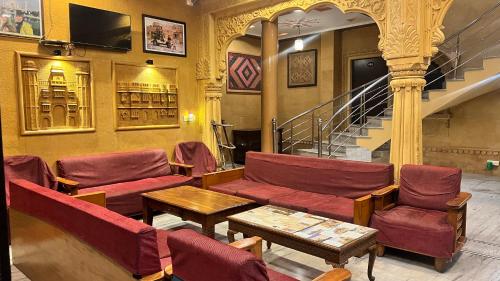 a room with red chairs and a table and stairs at Hotel Tokyo Palace in Jaisalmer