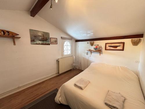 a bedroom with a white bed and a window at Maison de vacances, Piscine & Plage à pied in La Teste-de-Buch