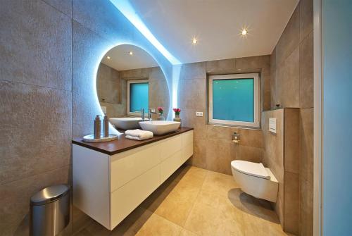 a bathroom with two sinks and a toilet at Ferienhaus Waldblick mit Whirlpool und Sauna in Hellwege