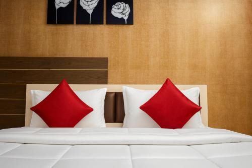 two red pillows sitting on a white bed at The Sky Comfort - Hotel The Heaven, Dwarka in Dwarka