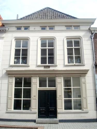 a white house with windows and a black door at Appartement Sint Jan in Den Bosch